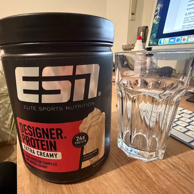 Unsere Extra Creamy Vanilla Milk Dose neben einem Glas auf dem Schreibtisch