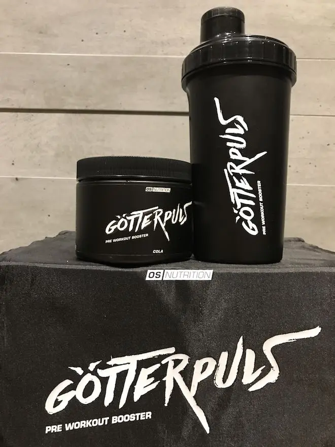 Götterpuls-Cola-Dose und schwarzer Shaker auf einem OS-Nutrition-Handtuch