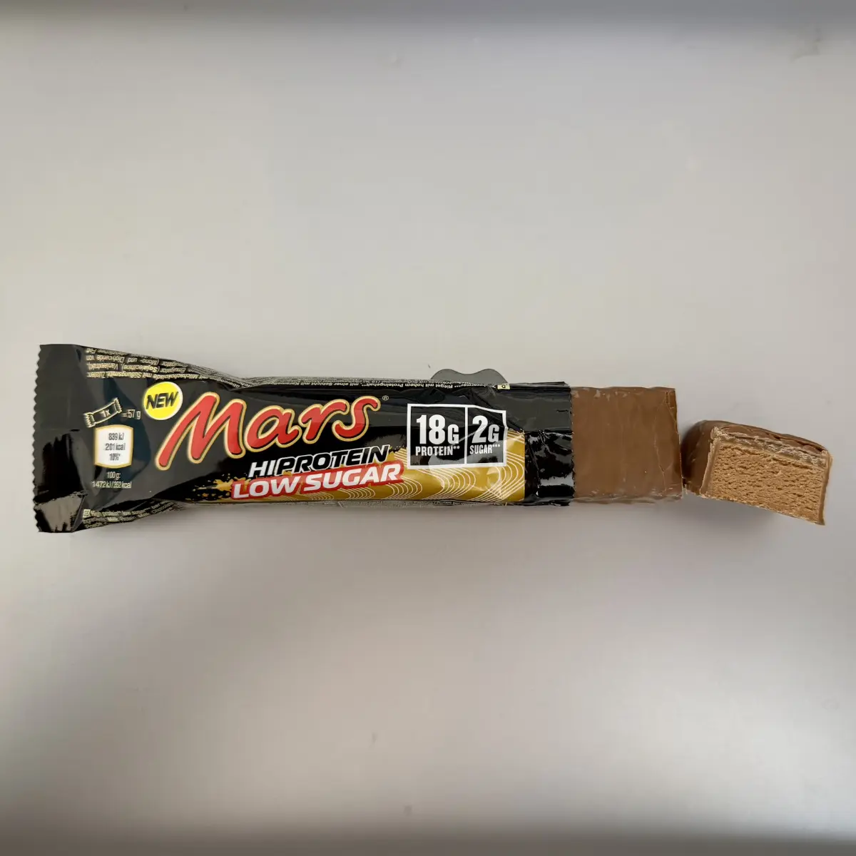 Aufgeschnittener Mars HiProtein Low Sugar Riegel mit sichtbarem Kern und geöffneter Verpackung