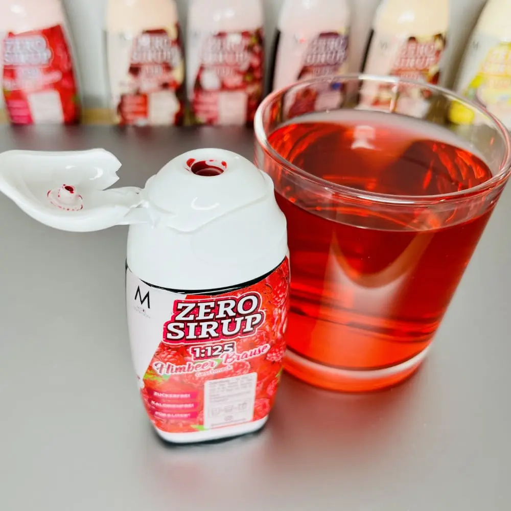 Geöffnetes Zero-Sirup-Fläschchen Himbeer Brause neben dem angemischten roten Getränk