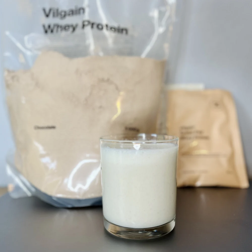 Angemischter Vilgain Shake mit Originalpackung und Probierbeutel aus unserem Test.