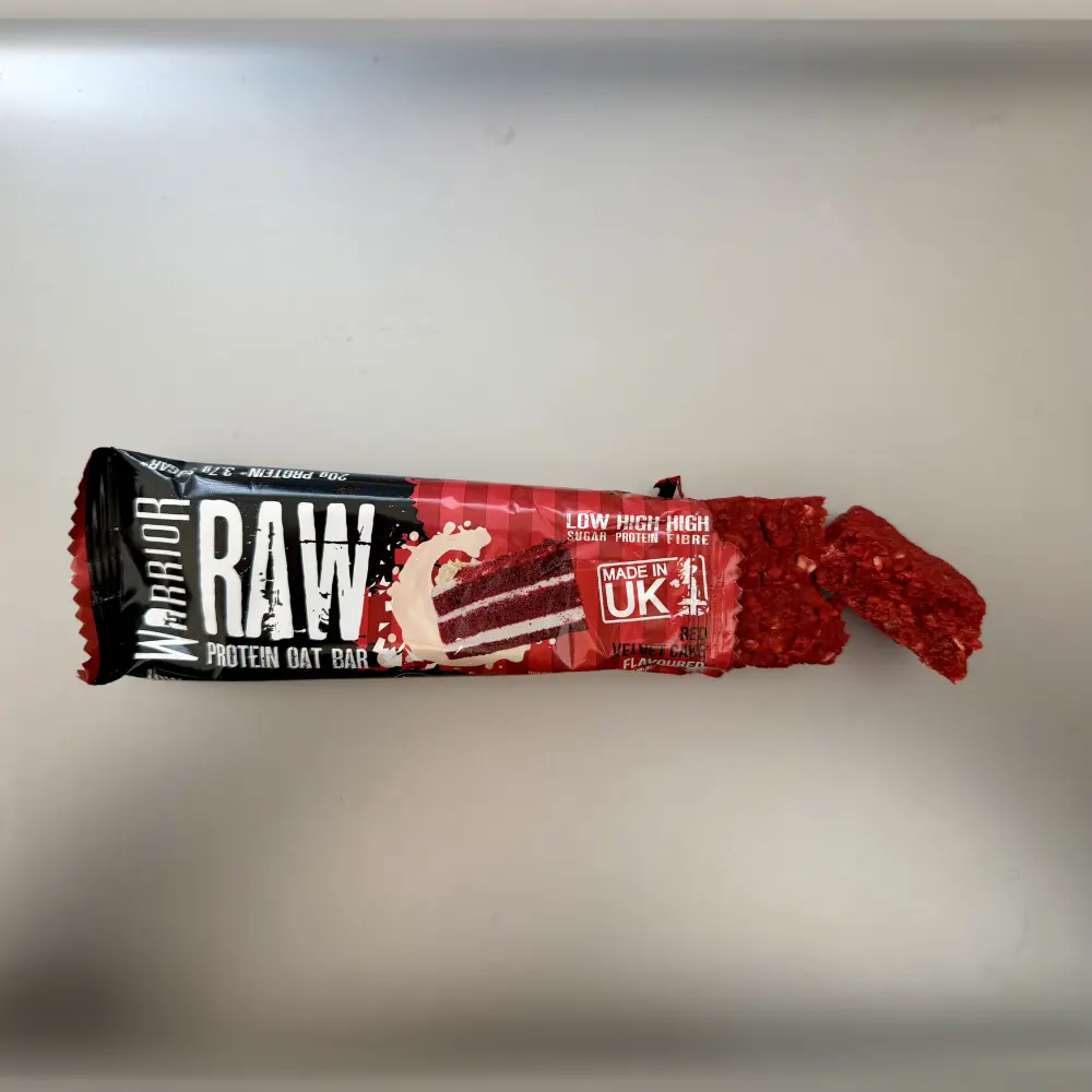 Geöffneter Warrior RAW Red Velvet Cake mit kräftig roter Hafermasse und abgebrochenem Stück