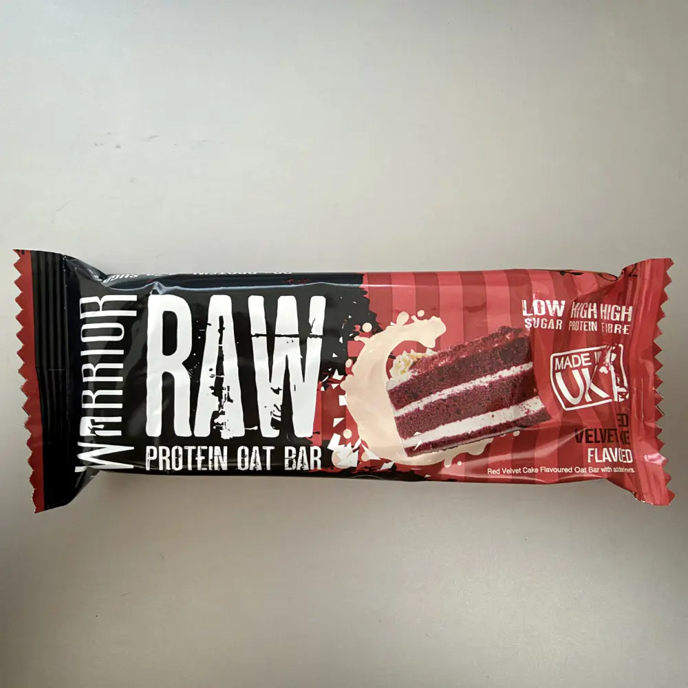 Schwarz-rote Einzelverpackung des Warrior RAW Protein Oat Bar Red Velvet Cake